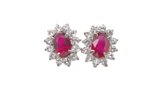 a pair of oval cut ruby halo stud earrings with diamond accents