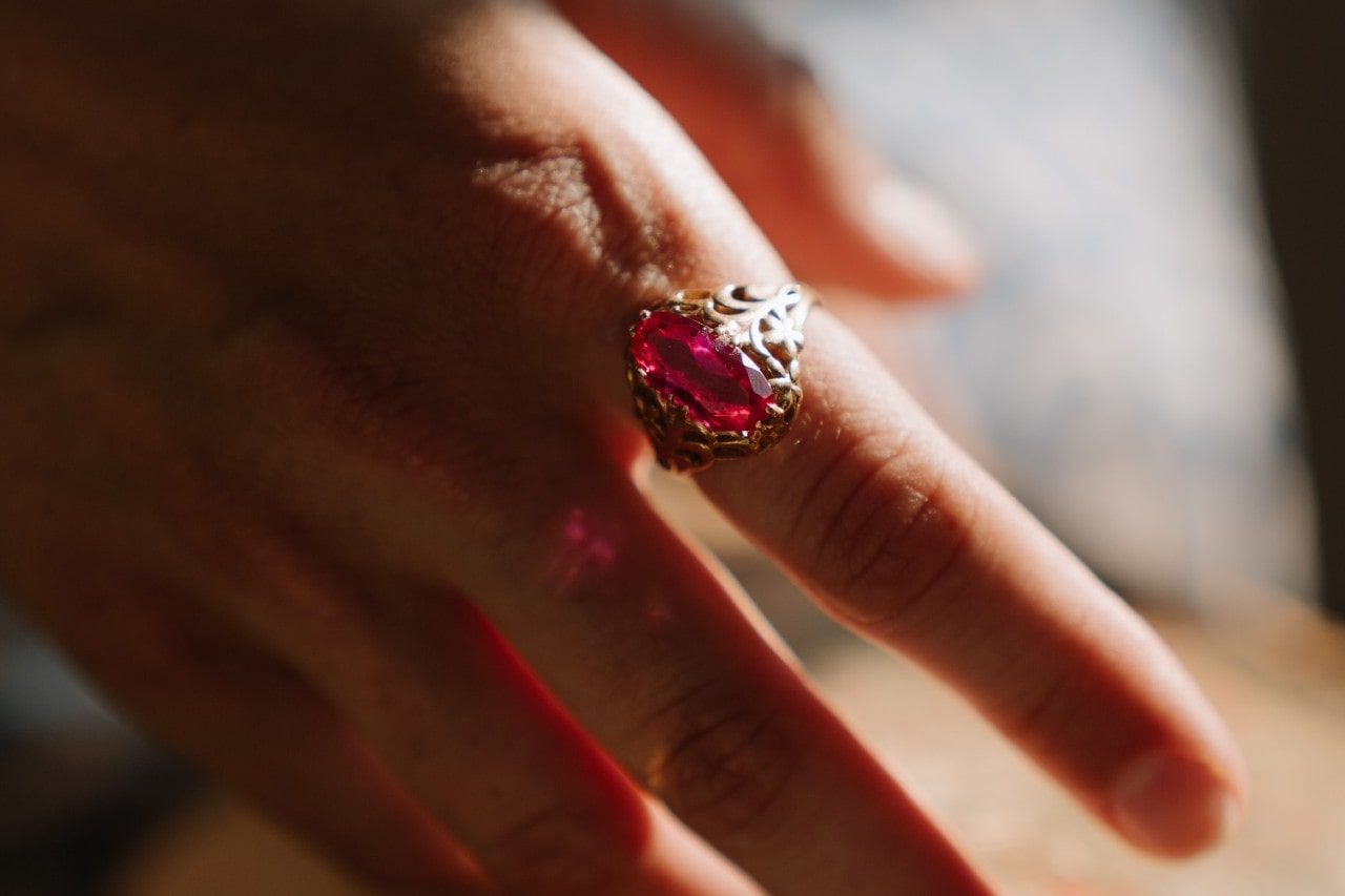 close up image of a person’s hand wearing an elaborate ruby fashion ring