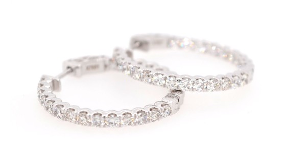 a pair of white gold hoop earrings lined with diamonds