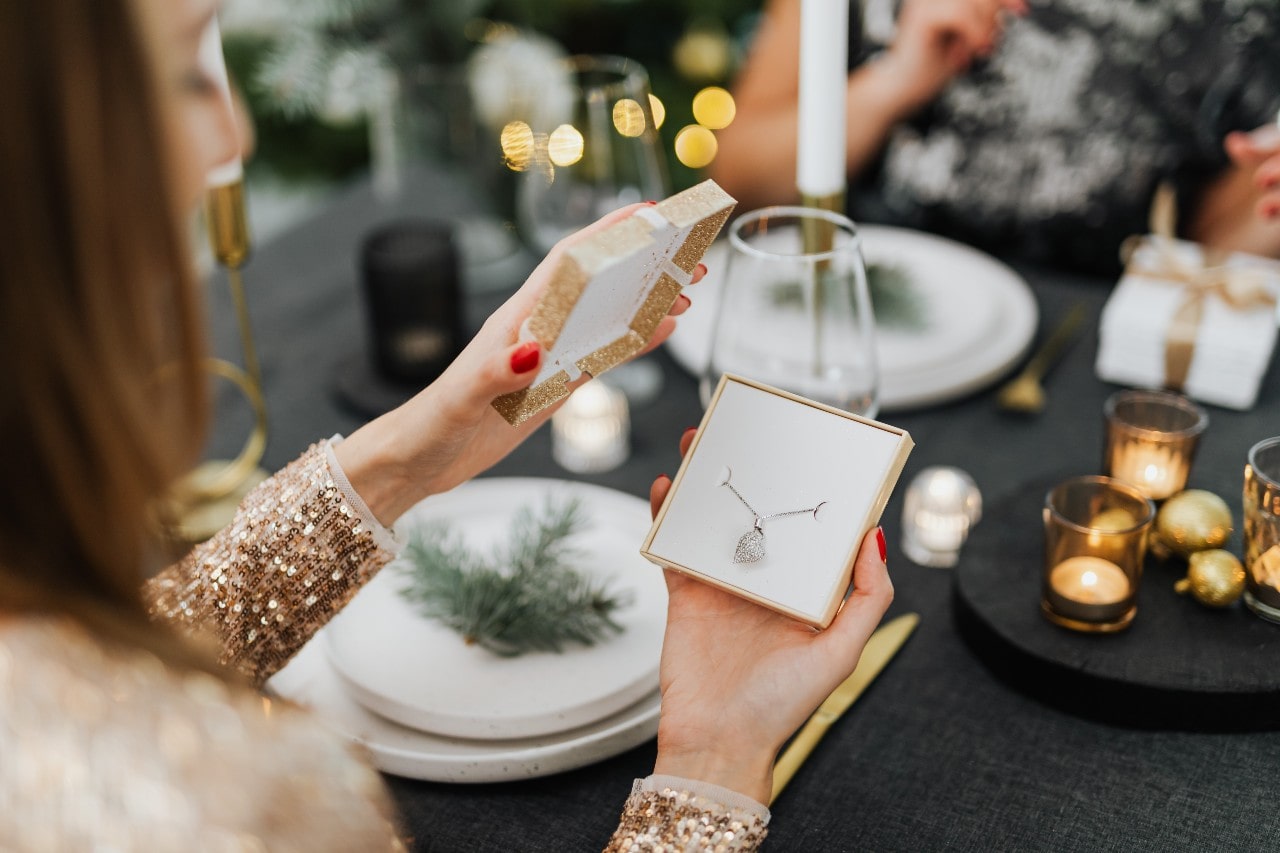 a woman opening a gift box containing a diamond necklace