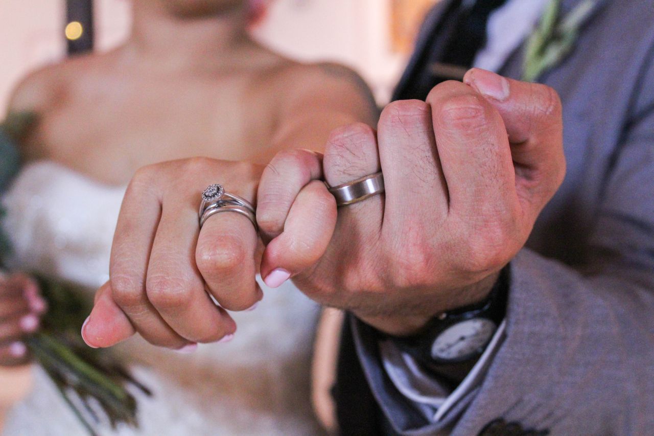 a man and a lady’s hands wearing wedding bands